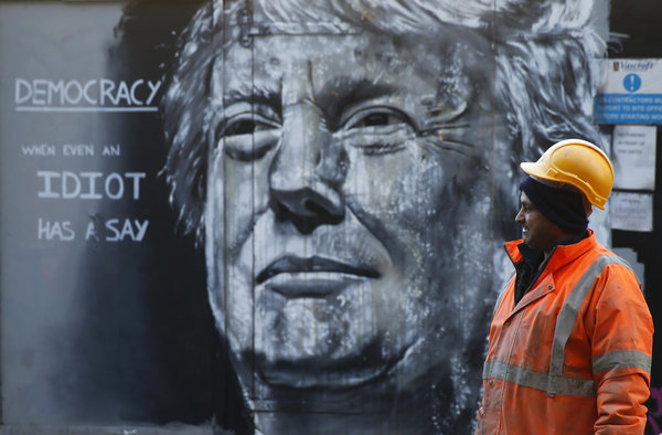 A construction worker stands in front of a piece of street art portraying prospective U.S. Presidential candidate Donald Trump, in east London, January 28, 2016. An online petition to bar Trump from entering the United Kingdom recently triggered a debate in Parliament after if was signed by over 500,000 people. REUTERS/Andrew Winning EDITORIAL USE ONLY. NO RESALES. NO ARCHIVE TPX IMAGES OF THE DAY